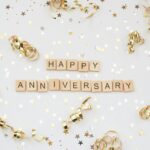 A festive looking background, with gold star trimmings and gold spirals with happy anniversary right at the center.