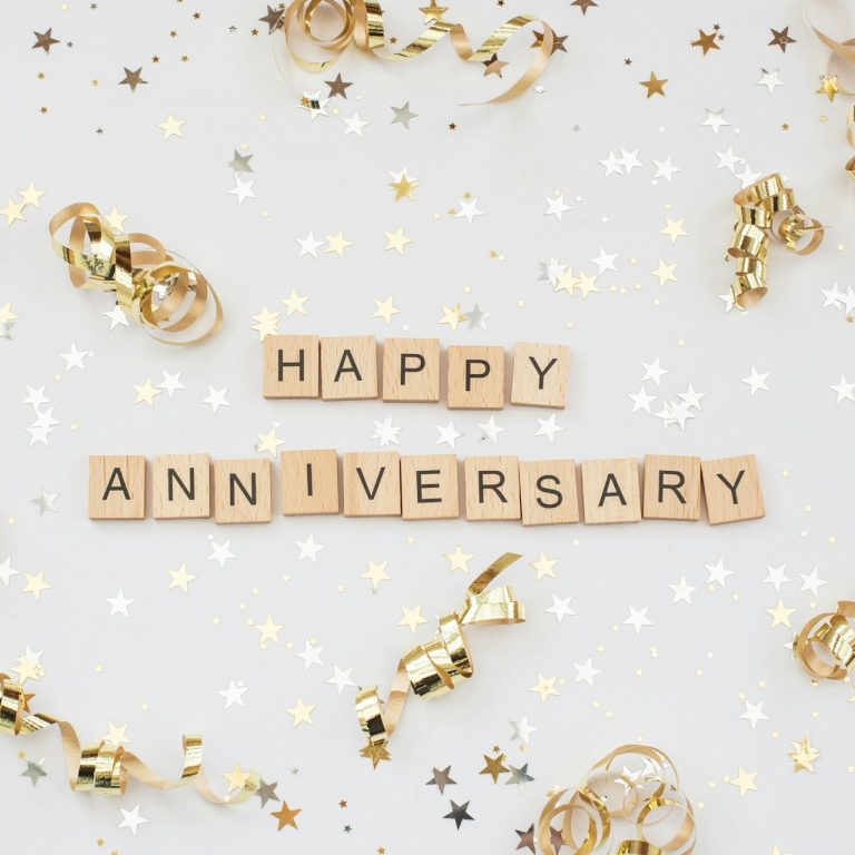A festive looking background, with gold star trimmings and gold spirals with happy anniversary right at the center.